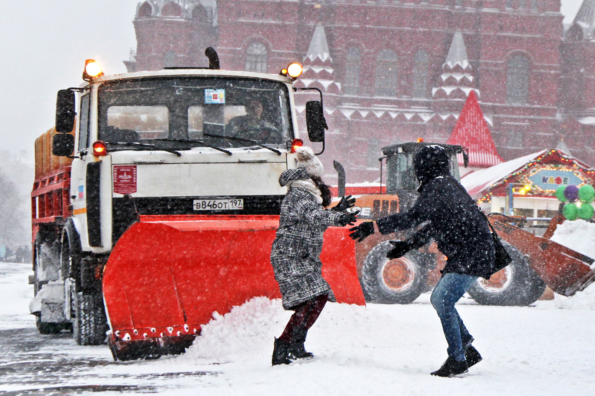 Seorang wanita panik saat menghindari mobil pembersih salju saat badai salju di Lapangan Merah, Moskow, Rusia, Sabtu (26/1).   