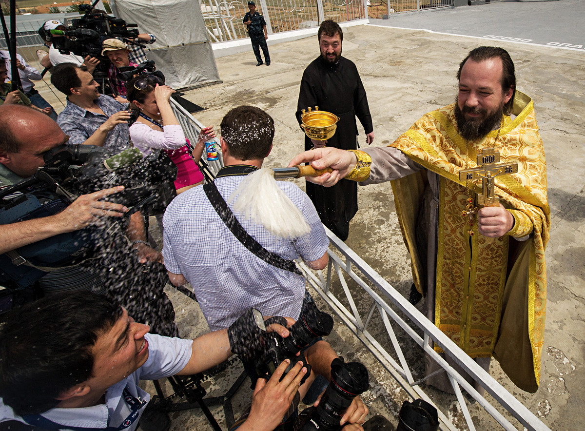 Seorang pastor Ortodoks memberkati awak media setelah memberkati roket Soyuz di Peluncuran Kosmodrom Baikonur.