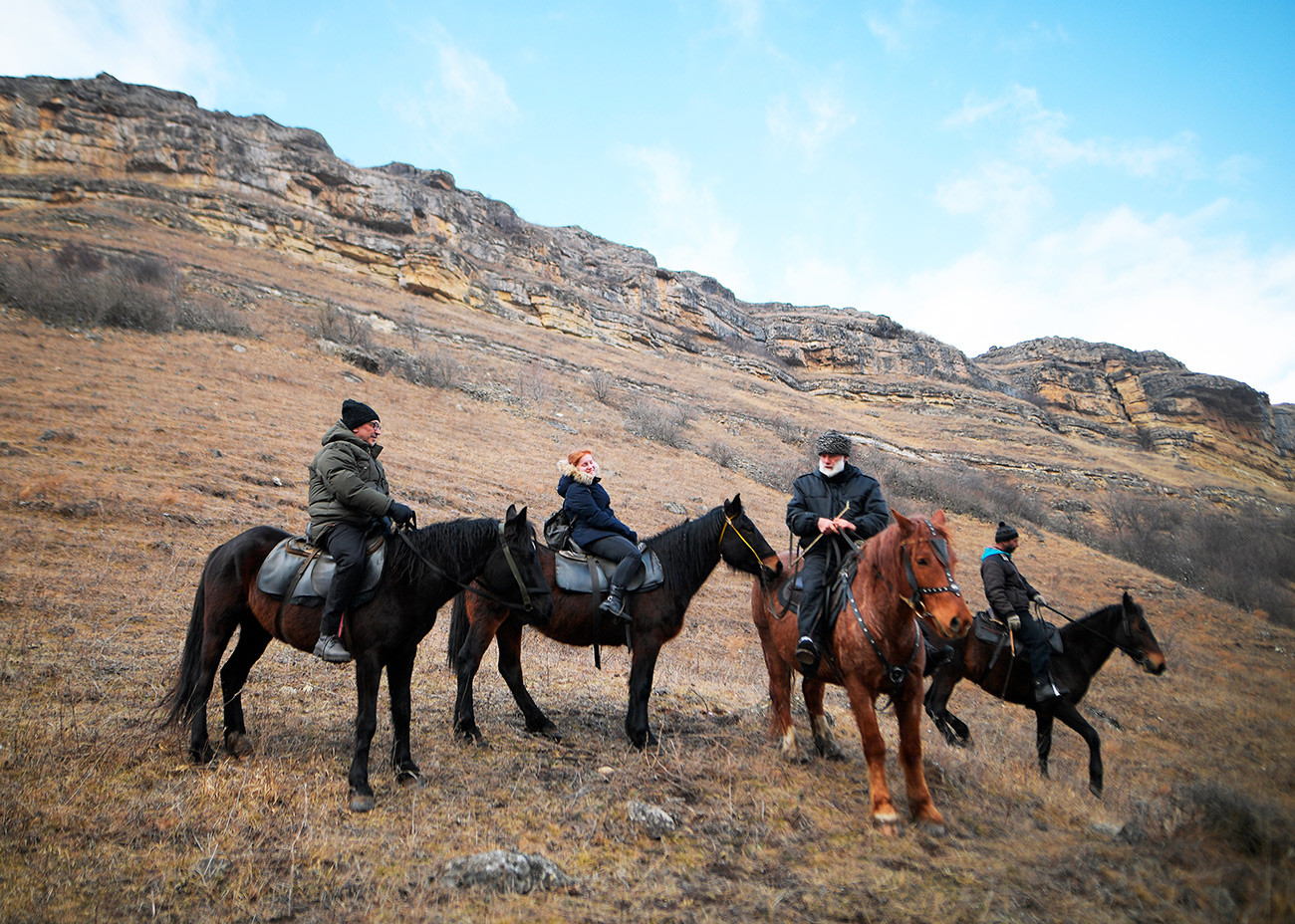 クラースヌィ・クルガン村で乗馬クラブ「グン」の馬に乗っている観光客。