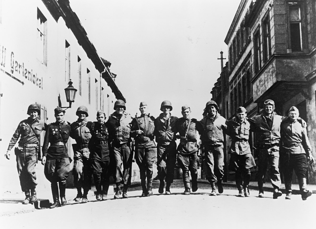 Насмејани амерички и руски војници загрљени ходају улицом на обали Елбе, Немачка, Други светски рат, 1945.