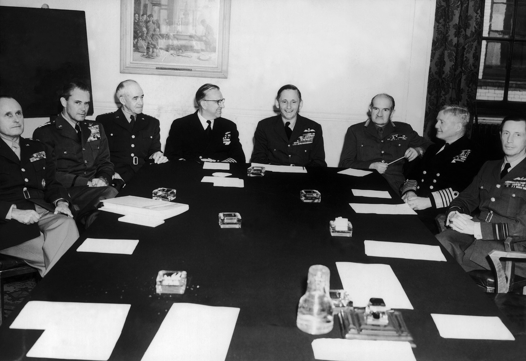 Autour de la table des négociations à Londres. De gauche à droite : le général-major Alfred M. Gruenther; le général Hoyst S. Vandenberg; le général Omar N. Bradley: l'Amiral Louis E. Denfield; le lord Tedder; le maréchal William Slim; l'amiral Fraser et le maréchal William Elliot.