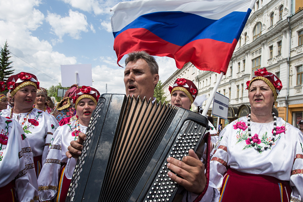 Orang-orang berkostum etnik ikut serta dalam parade Hari Rusia di Omsk.