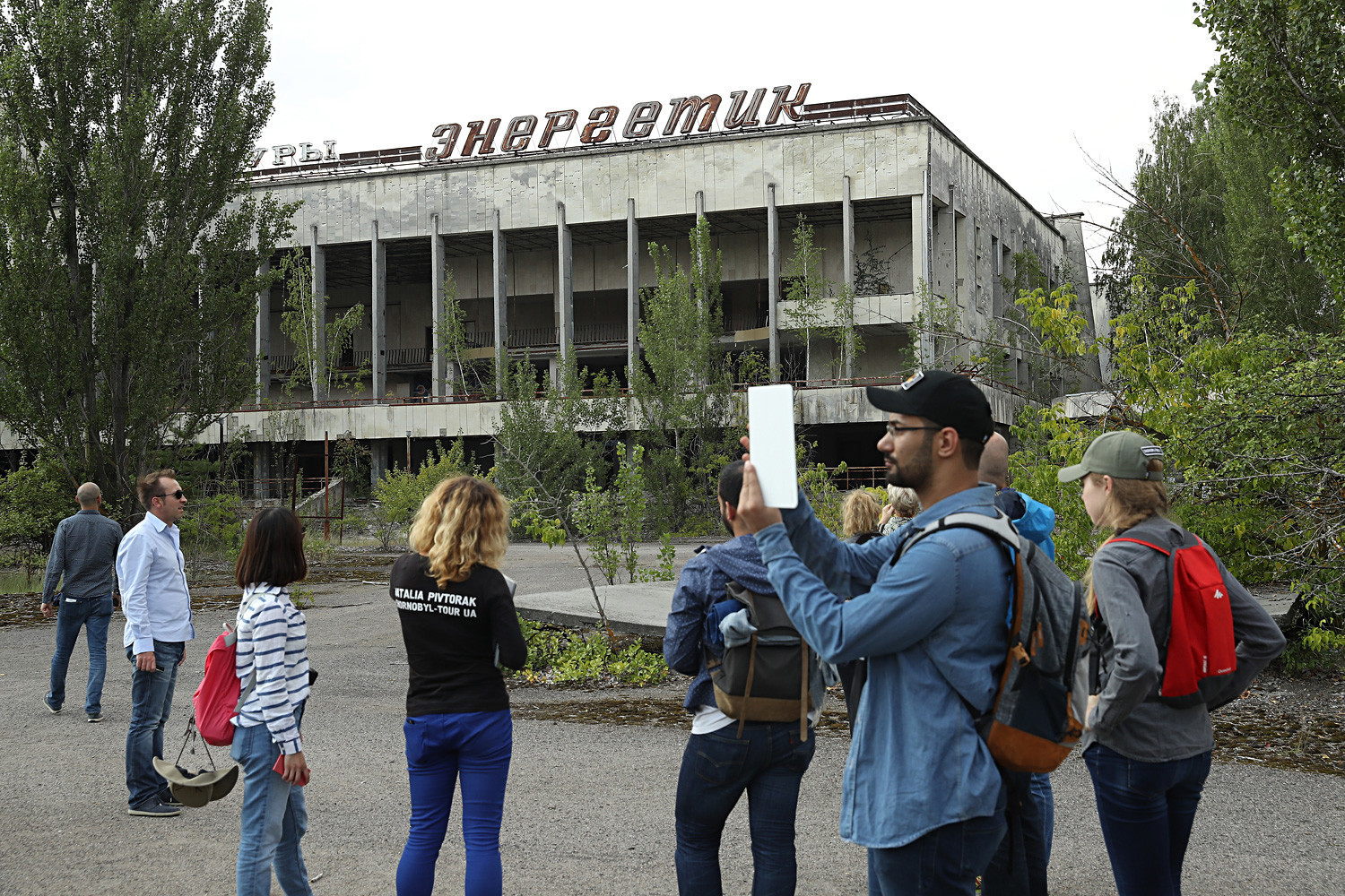 Туристи прават фотографии пред поранешниот културен центар Енергетика во градот-призрак  Припјат (Украина) во август 2017 година.