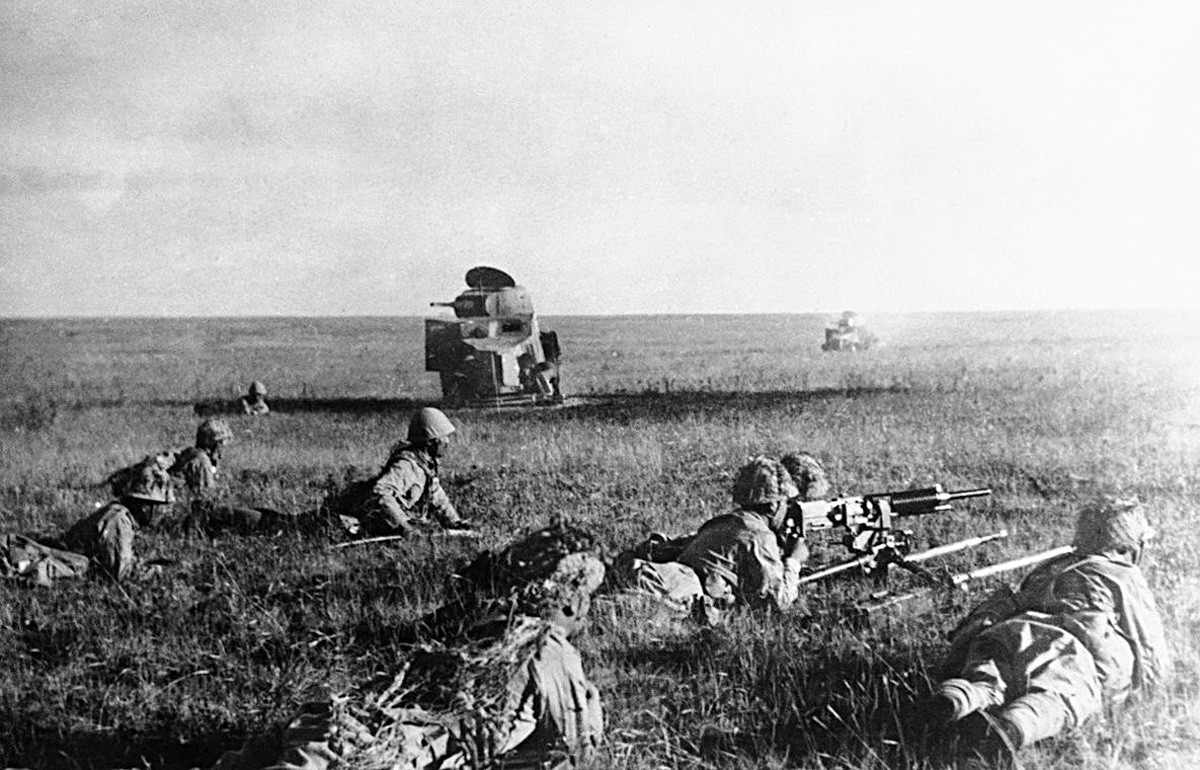 日本兵が、破壊されたソビエト戦車の前で匍匐前進する。