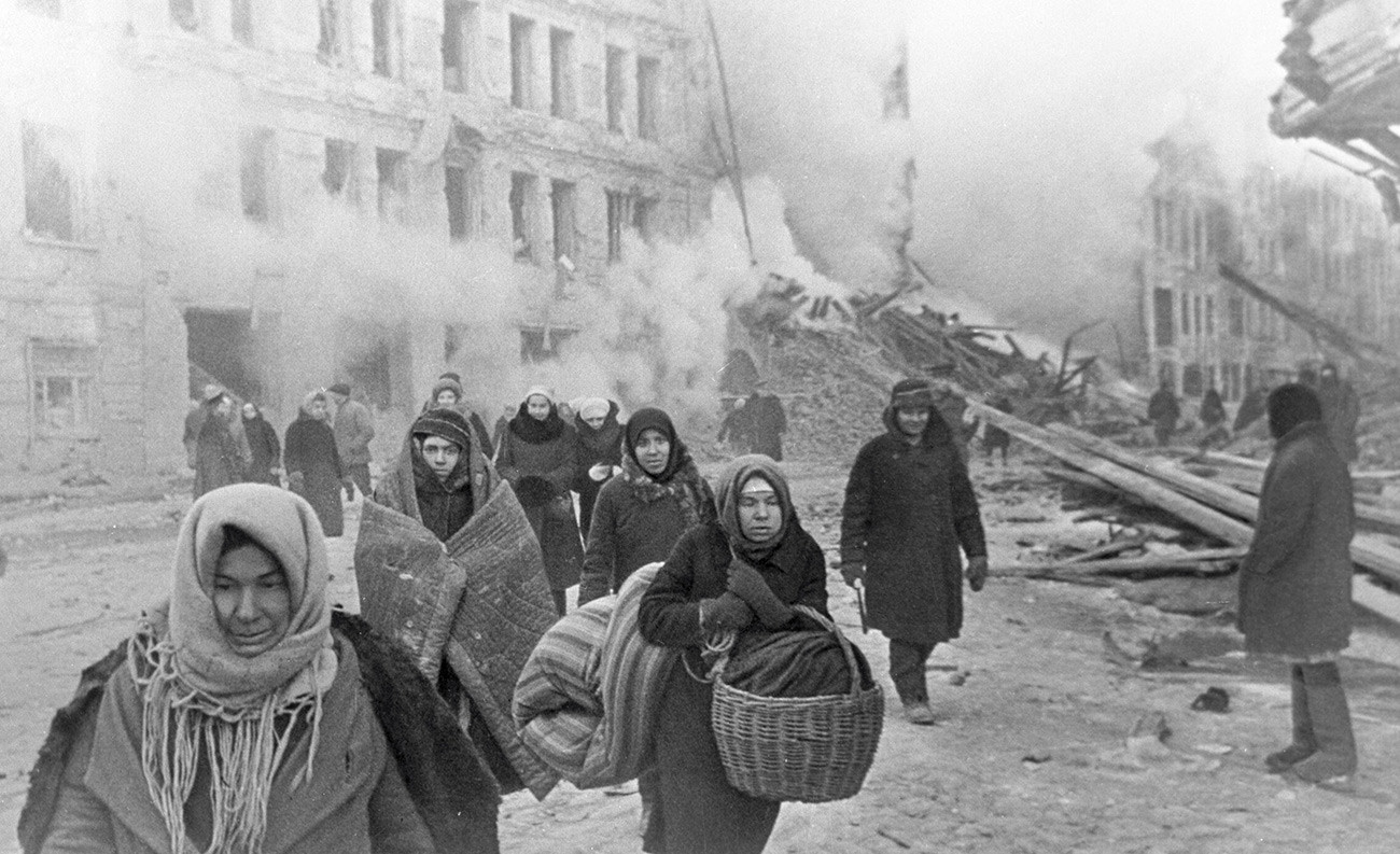 Stadtbewohner verlassen ihre durch Bombenangriffe der Nazis zerstörten Häuser.

