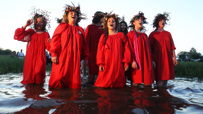 Young women walk in the water wearing wreaths during Ivan Kupala Day celebrations at Lake Ilmen in Novgorod Region. 