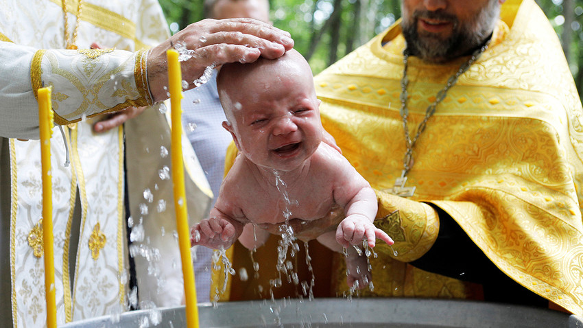 Para pendeta Ortodoks membaptis seorang anak selama upacara pembaptisan massal pada peringatan Kristenisasi Rusia, yang kemudian dikenal sebagai Rus Kiev, di Stavropol, Rusia, 28 Juli 2019.