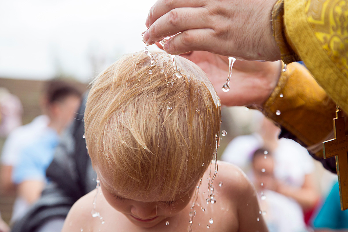 Seorang anak mengikuti upacara pembaptisan massal.
