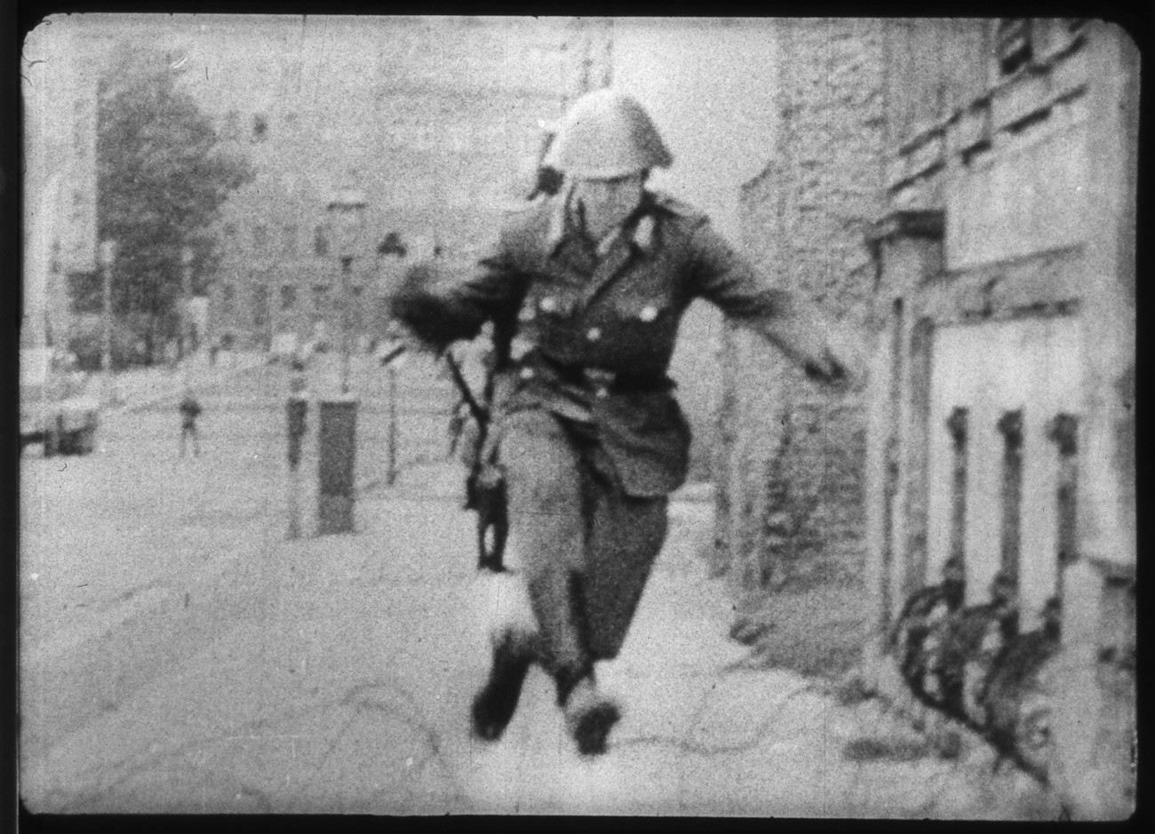 Tentara Penjaga Jerman Timur Conrad Schumann melompati kawat berduri ketika melarikan diri ke Berlin Barat.