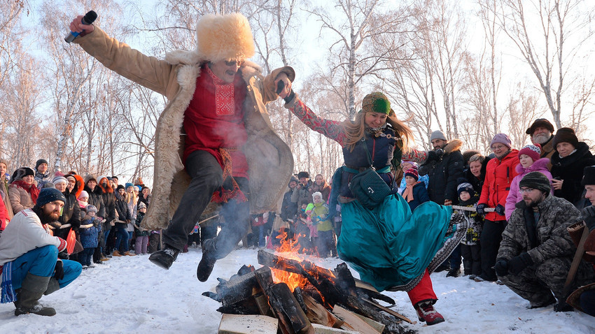 Los participantes saltan sobre el fuego en el festival de entretenimiento y diversión Sviatki 2017 en la región de Cheliábinsk.