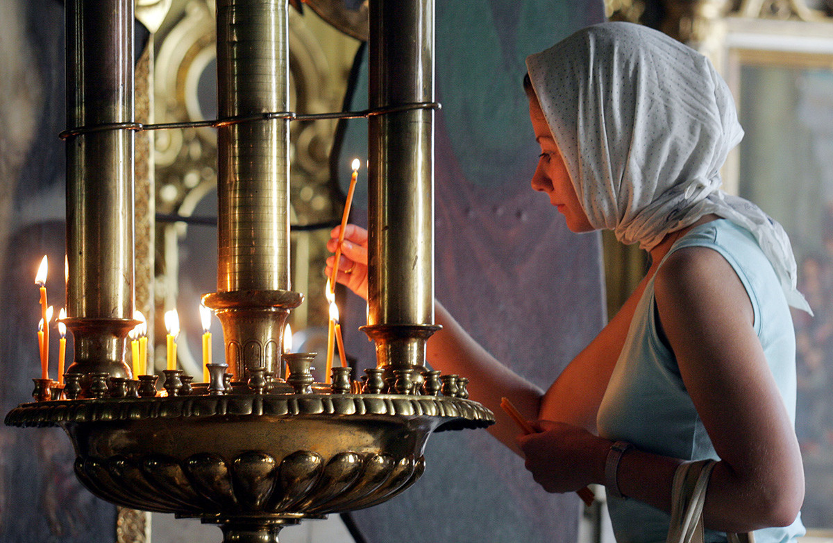 Russian woman lights a candle during a remembering church service in Moscow