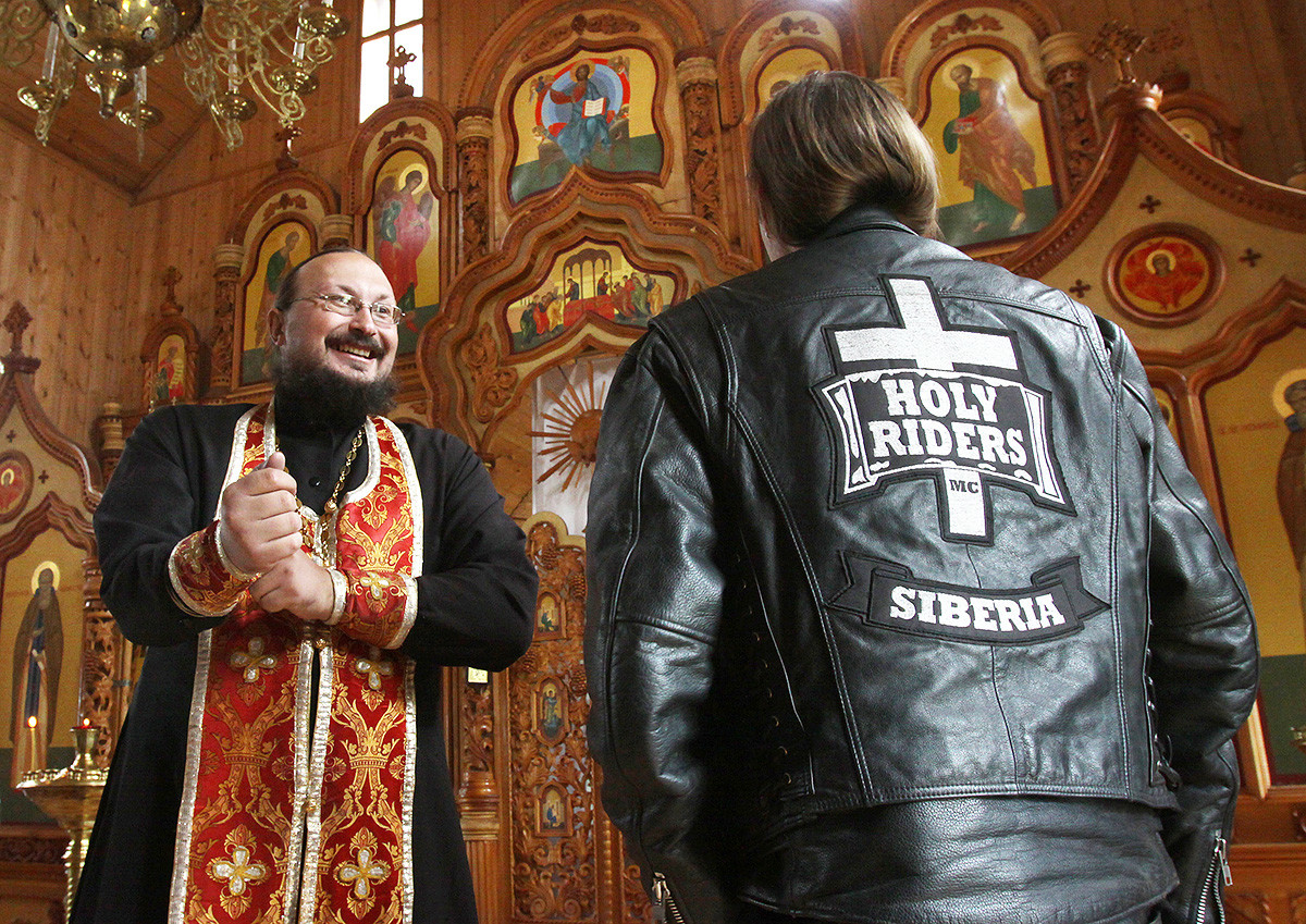 Russian Orthodox priest Father Alexander (L) speaks with a biker at a church in Kemerovo on July 31, 2010. Father Alexander, himself an avid biker, makes several religious biker pilgrimages a year to various churches in the area