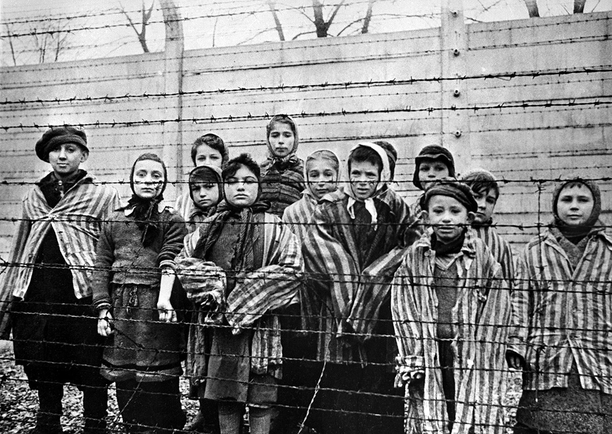 Kinder hinter einem Stacheldrahtzaun im KZ Auschwitz