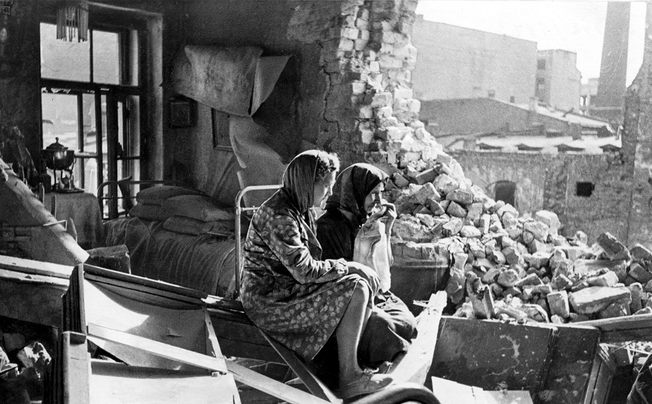 Dua orang perempuan duduk di antara puing-puing setelah Jerman mengebom Leningrad. Demi memaksa para pejuang Rusia menyerah, pasukan Jerman mengebom habis-habisan kota tersebut sehingga menewaskan banyak warga sipil.