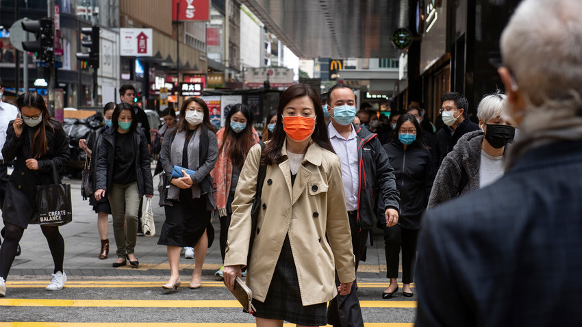 Прохожие в защитных масках на одной из улиц в Гонконге.