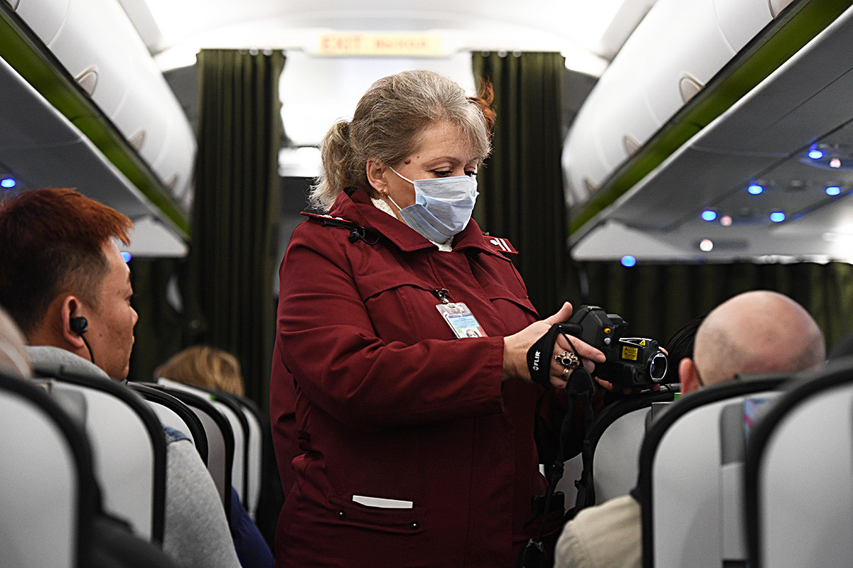 Trabajadora de la estación de cuarentena y sanidad comprueba la temperatura de los pasajeros llegados de Pekín a bordo de un avión en el aeropuerto de Novosibirsk, Rusia.  