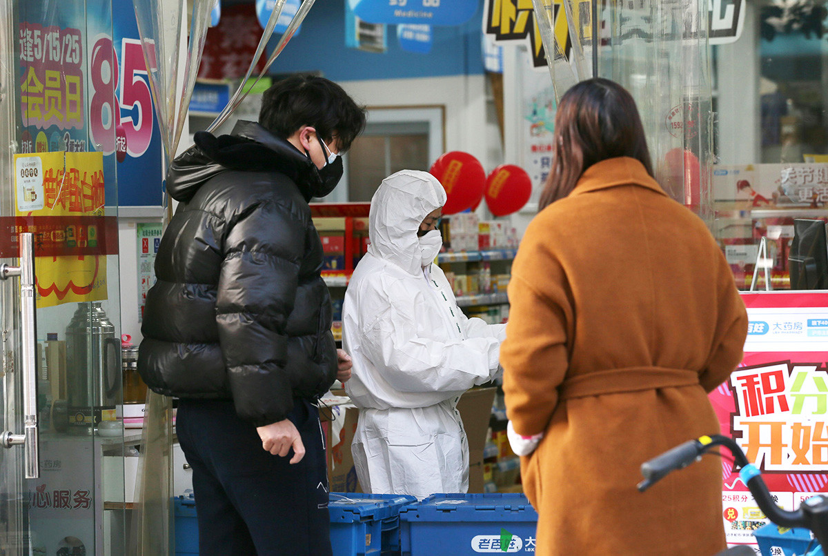 Seorang pekerja mengenakan pakaian pelindung saat melayani pelanggan di apotek setelah wabah virus corona merebak di Wuhan.