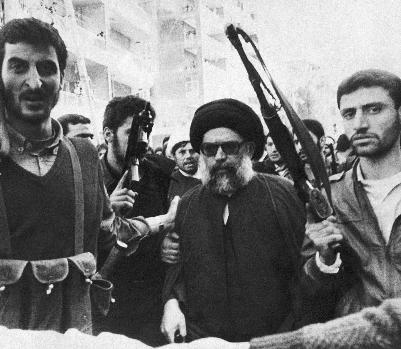 Мохамед Хюсеин Фадлала, заобиколен от охраната си  в южно предградие на Бейрут, Ливан, отива на погребалната церемония на 75-те жертви на експлозия на автомобилна бомба. 9 март 1985 г.