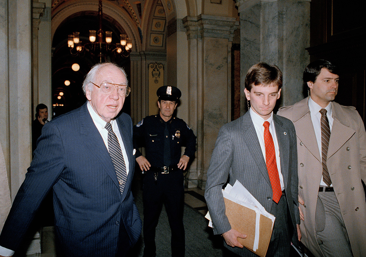 Direktur CIA William Casey berjalan melewati seorang polisi Capitol Hill pada Jumat, 21 November 1986.
