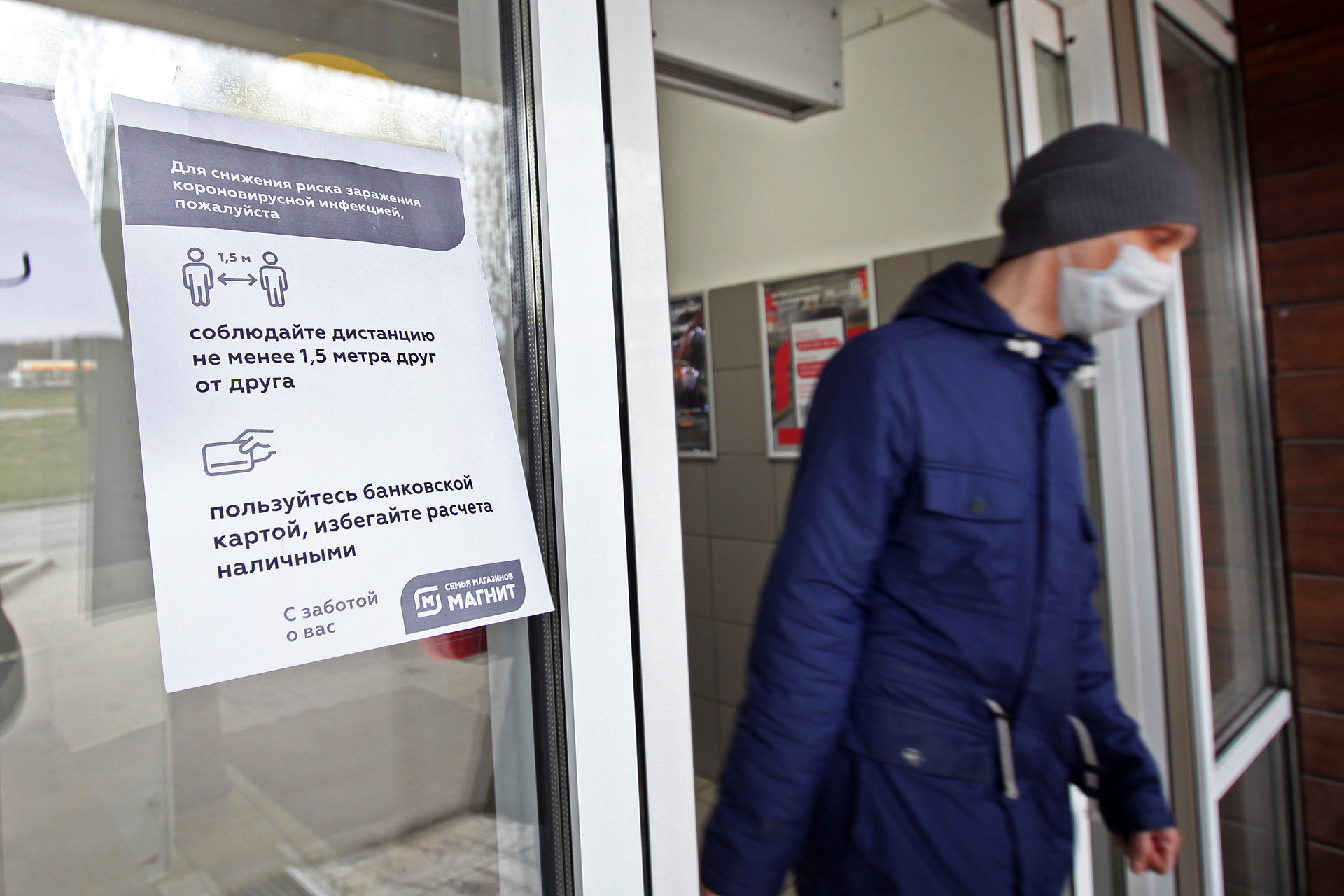 Pengumuman untuk menjaga jarak dan pembayaran menggunakan kartu ditempel di sebuah toko di Moskow, Senin (30/3)