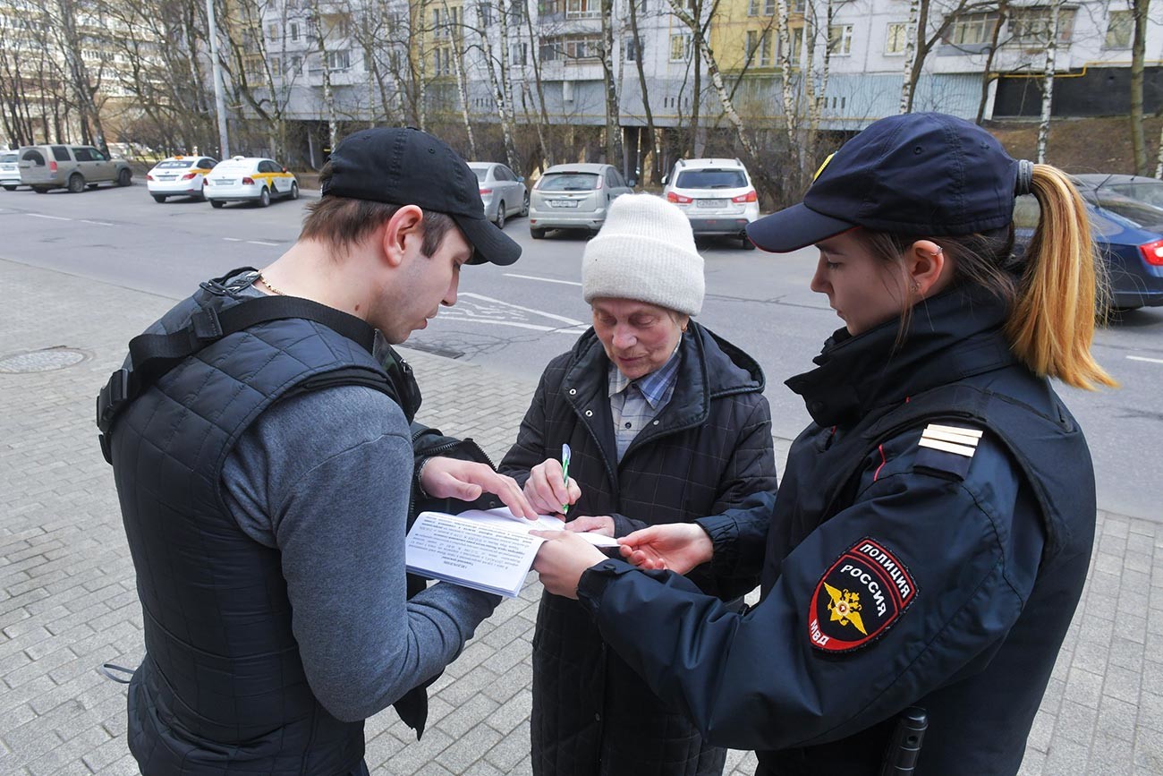 Guardas conversam com idosa em Moscou.