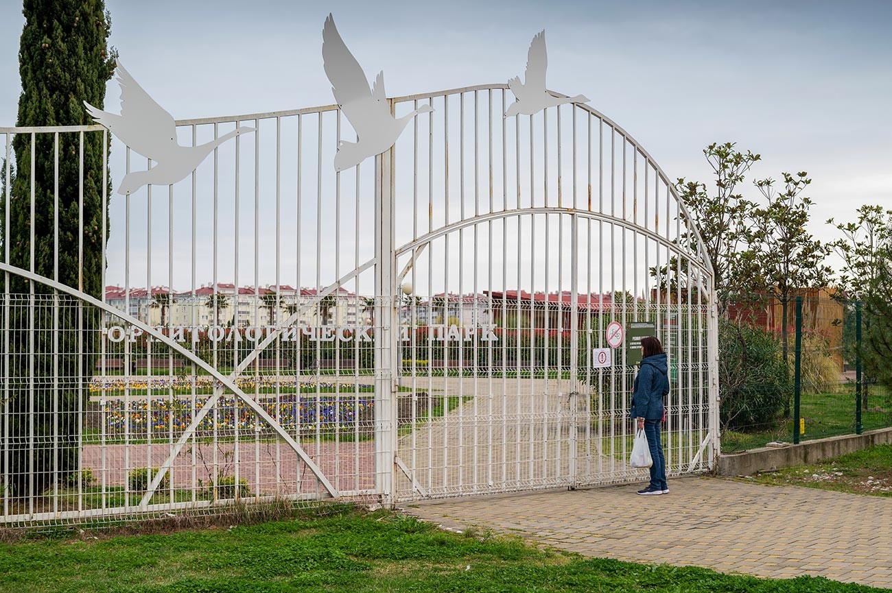 Mulher lê placa sobre fechamento de parque em Sôtchi devido à epidemia de coronavírus.