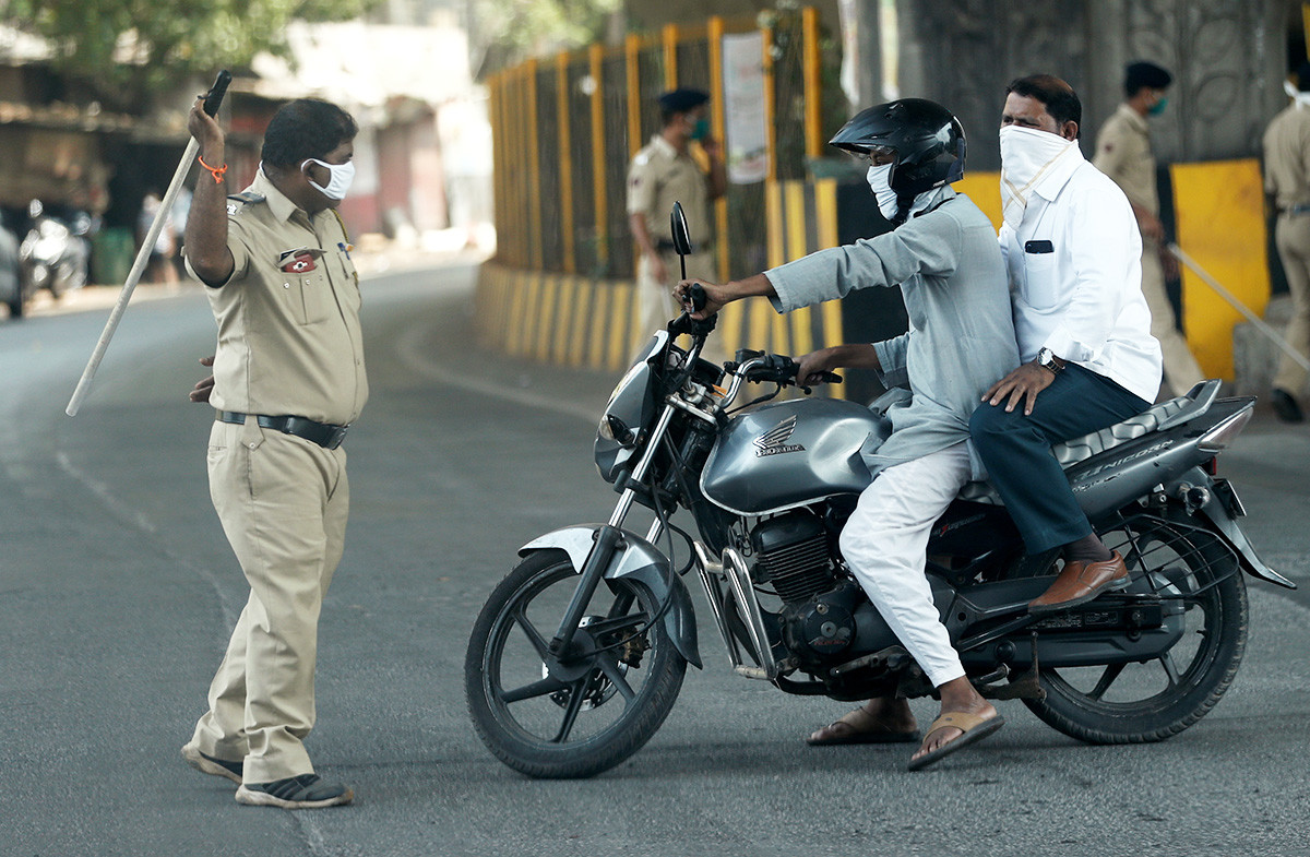 A policeman wields his baton at a man riding a motorbike as a punishment for breaking the lockdown rules, after India ordered a 21-day nationwide lockdown to limit the spreading of coronavirus disease (COVID-19) in Mumbai, India