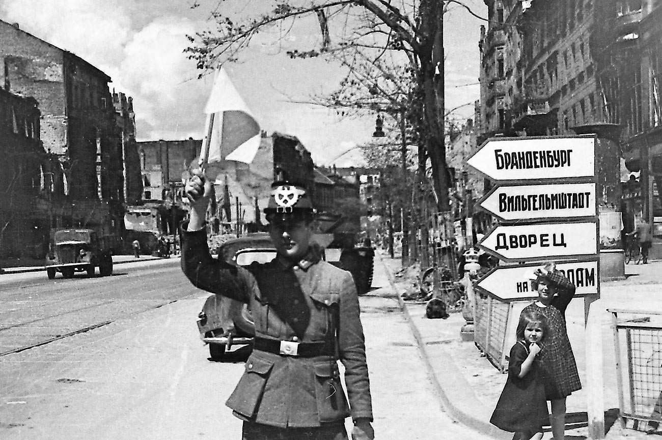 イリヤ・アロンス。旗を持った赤軍女性兵士に代わって仕事を始めた戦後初のドイツ人交通整理員。戦後のベルリンにて。1945年夏。