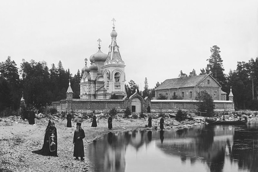 Un grupo de monjes y un schemnik junto a las celdas de Konevski, parte del monasterio de la Natividad en la orilla del lago Ladoga, 1892