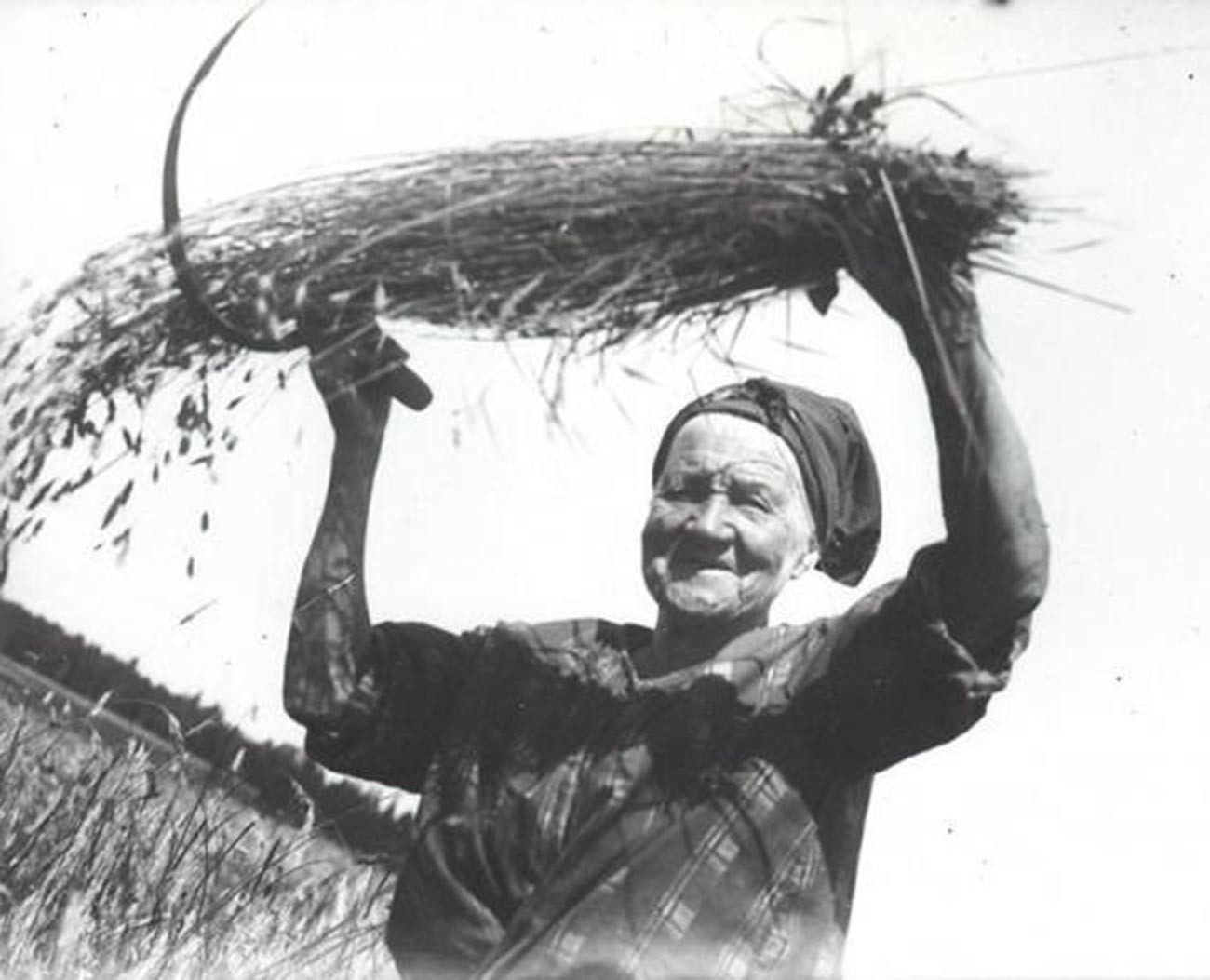 Eine alte Frau hält einen Getreidebündel
