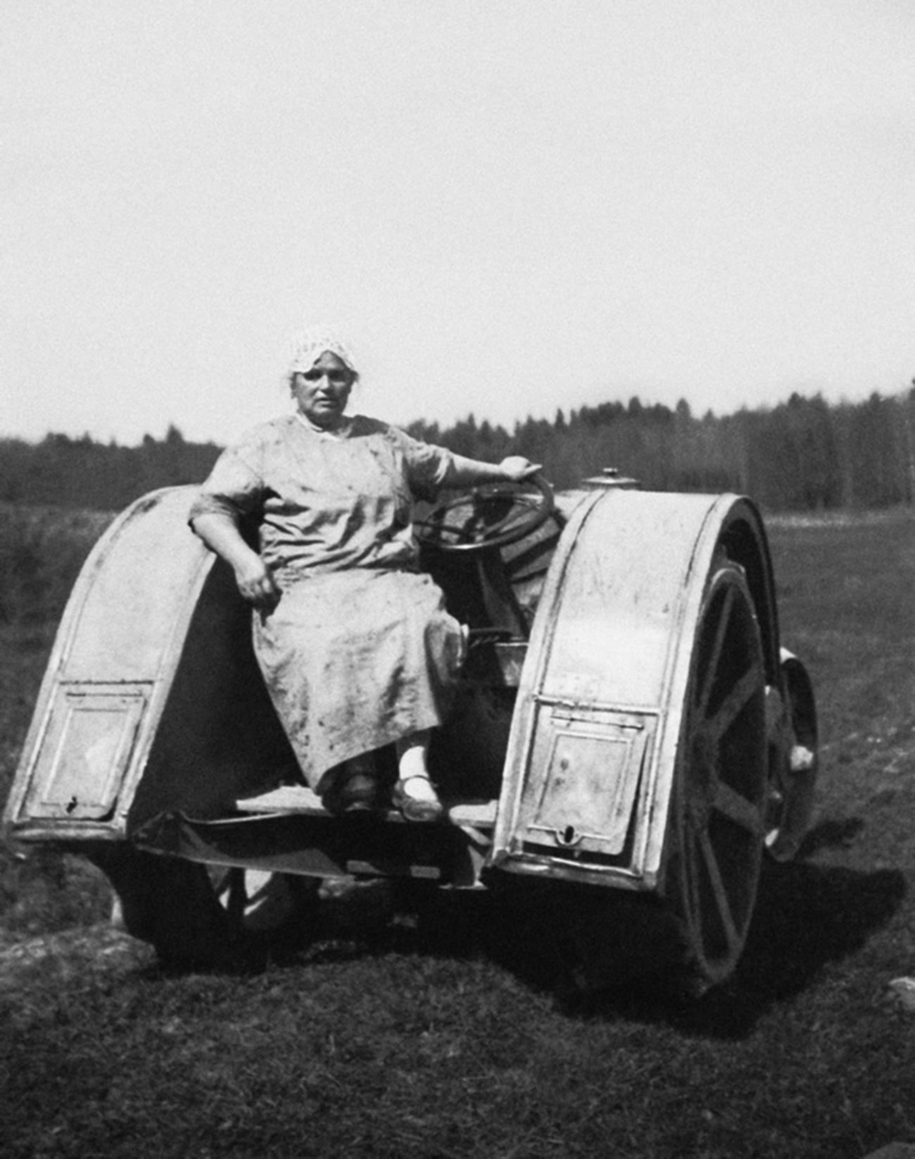 Seorang perempuan tua berpose di atas traktor.