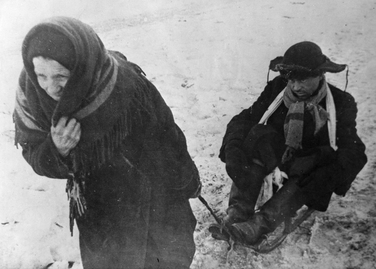 Mulher puxa de trenó marido em estado de inanição, durante o Cerco a Leningrado