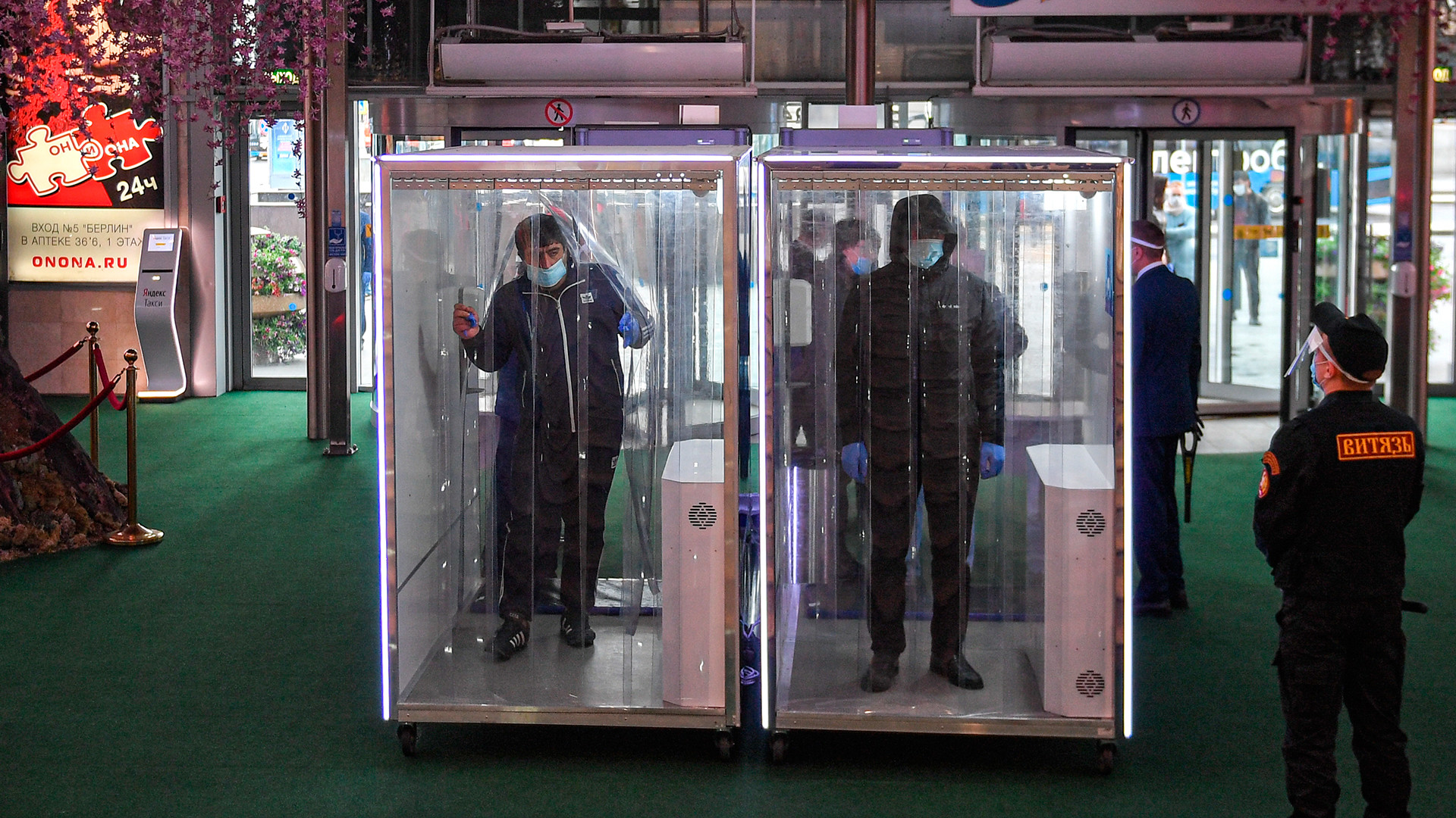 Des visiteurs passent par les cabines de désinfection à l'entrée du centre commercial Evropeïski
