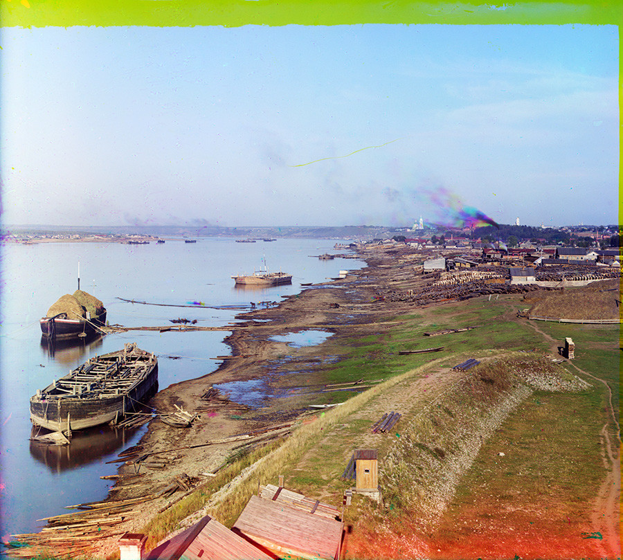 View up left bank of Kama River (taken from railroad bridge). Beneath the smoke plume: bell tower & Cathedral of the Transfiguration. Smoke is multicolored because of motion during the three sequential exposures of the negative. Summer 1909 