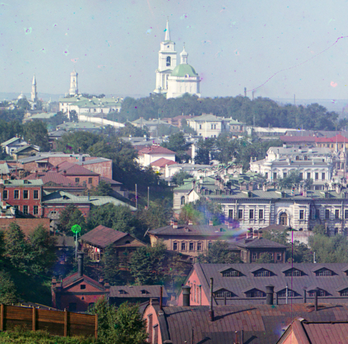 View of central Perm from City Hills. In distant background from left: minaret of Main Mosque, bell tower of Trinity Cathedral. Center: Transfiguration Cathedral. Center far right: side & back of Meshkov House. All buildings linked by Monastery Street. Summer 1909.