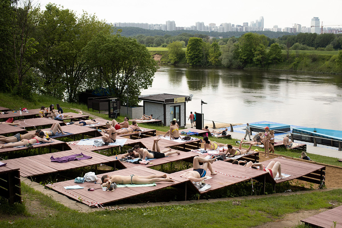Orang-orang berjemur di salah satu taman di tepi Sungai Moskow selama hari yang panas di ibu kota, Rusia, Selasa, 9 Juni 2020.