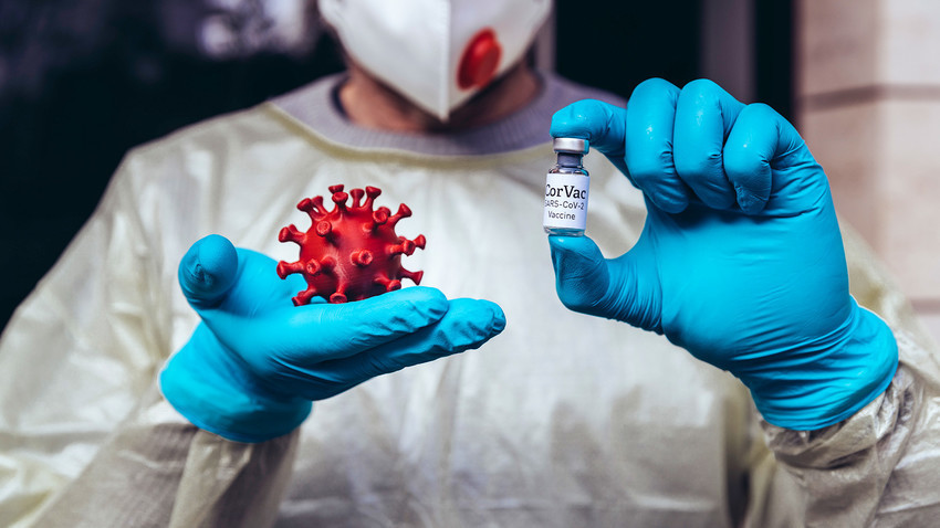 Медицински радник држи модел Корона вируса и вакцину.