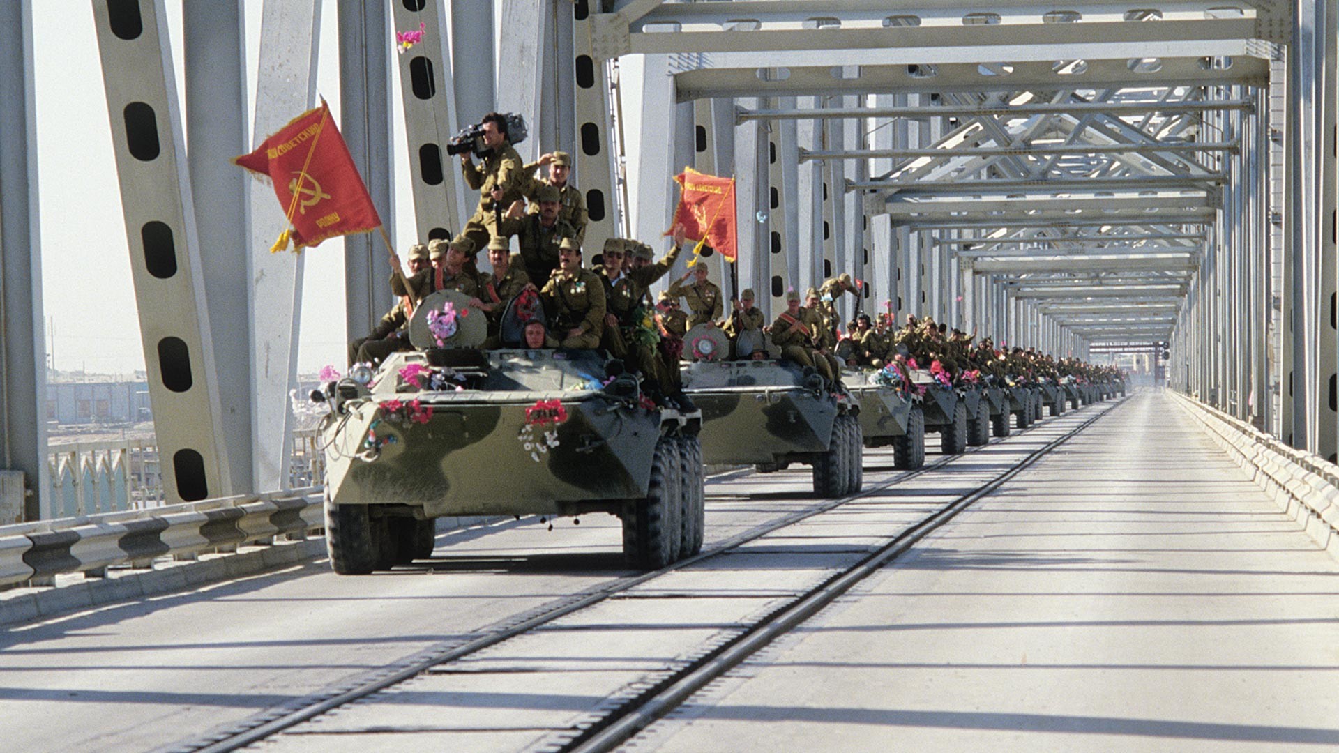 A column of armored vehicles crosses the Afghan-Soviet border through the Friendship bridge lying over the Amu Darya river.