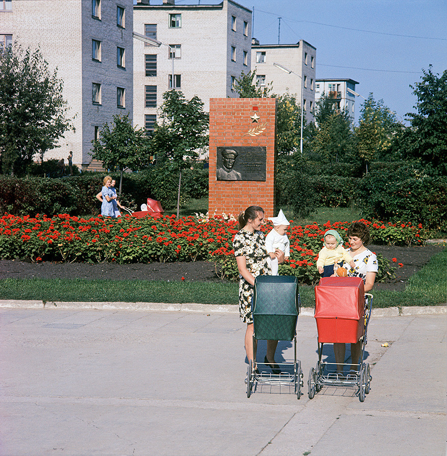 Ibu muda di kota Novolukoml, Wilayah Vitebsk. Di belakangnya berdiri sebuah monumen untuk komandan partisan F. Ozmitel, 1978.