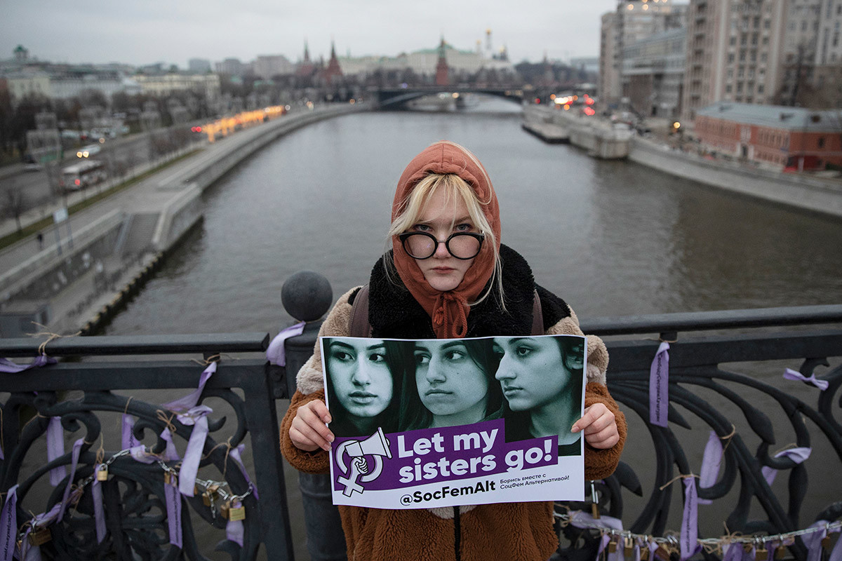 Eine Frau hält ein Schild mit Fotos von Chatschaturjan-Schwestern während einer Aktion gegen häusliche Gewalt in Moskau