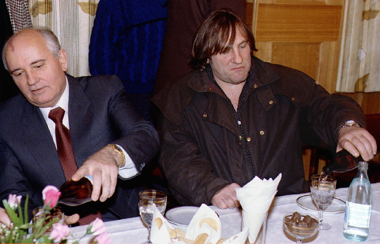 Бившият съветски лидер Михаил Горбачов (вляво) и френската филмова звезда Жерар Депардийо си наливат минерална вода  на среща в Москва. Тогава френският актьор идва на филмовия фестивал.
