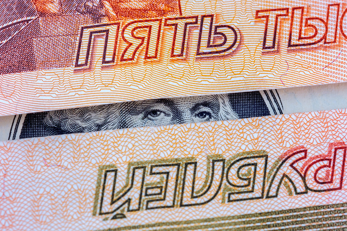 Između dvije novčanice od pet rubalja vide se oči Georgea Washingtona na novčanici od jednog dolara.
