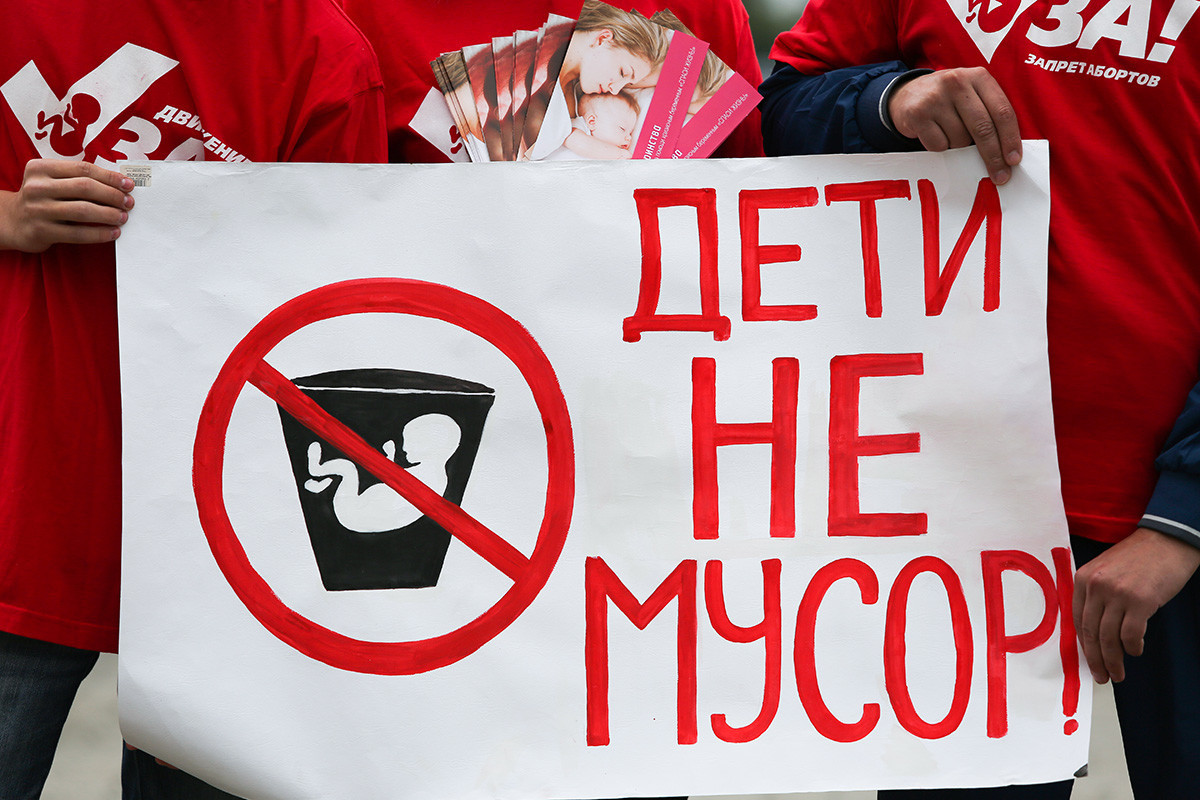 Aktivisti proti splavu pred prednatalnim centrom držijo plakat z napisom 