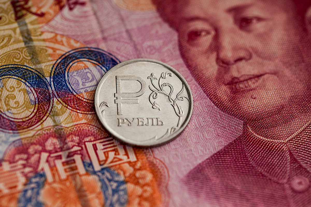 Курсот на рубљата во однос на јуанот. Во крупен план е прикажана монета од една рубља и сто кинески јуани. 