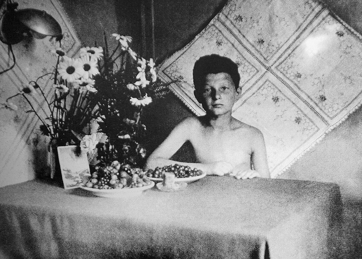 Деветогодишњи или десетогодишњи Алекс Курзем седи сам за столом, око 1944. године.