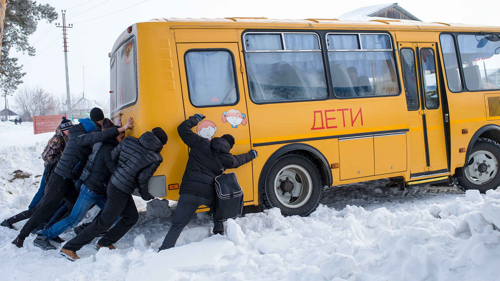 Мужчины толкают застрявший в снегу автобус во время сельской зимней спартакиады в селе Евгащино Омской области. 
