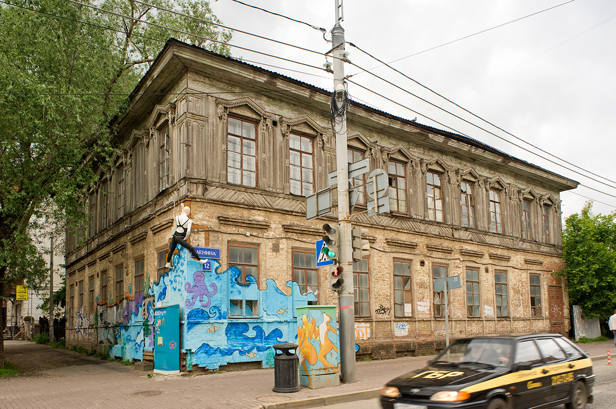 19th-century wooden house (log structure with plank siding on stuccoed brick ground story) at corner of Ostrovsky & Lenin Streets. Decorated with street art. June 15, 2014
