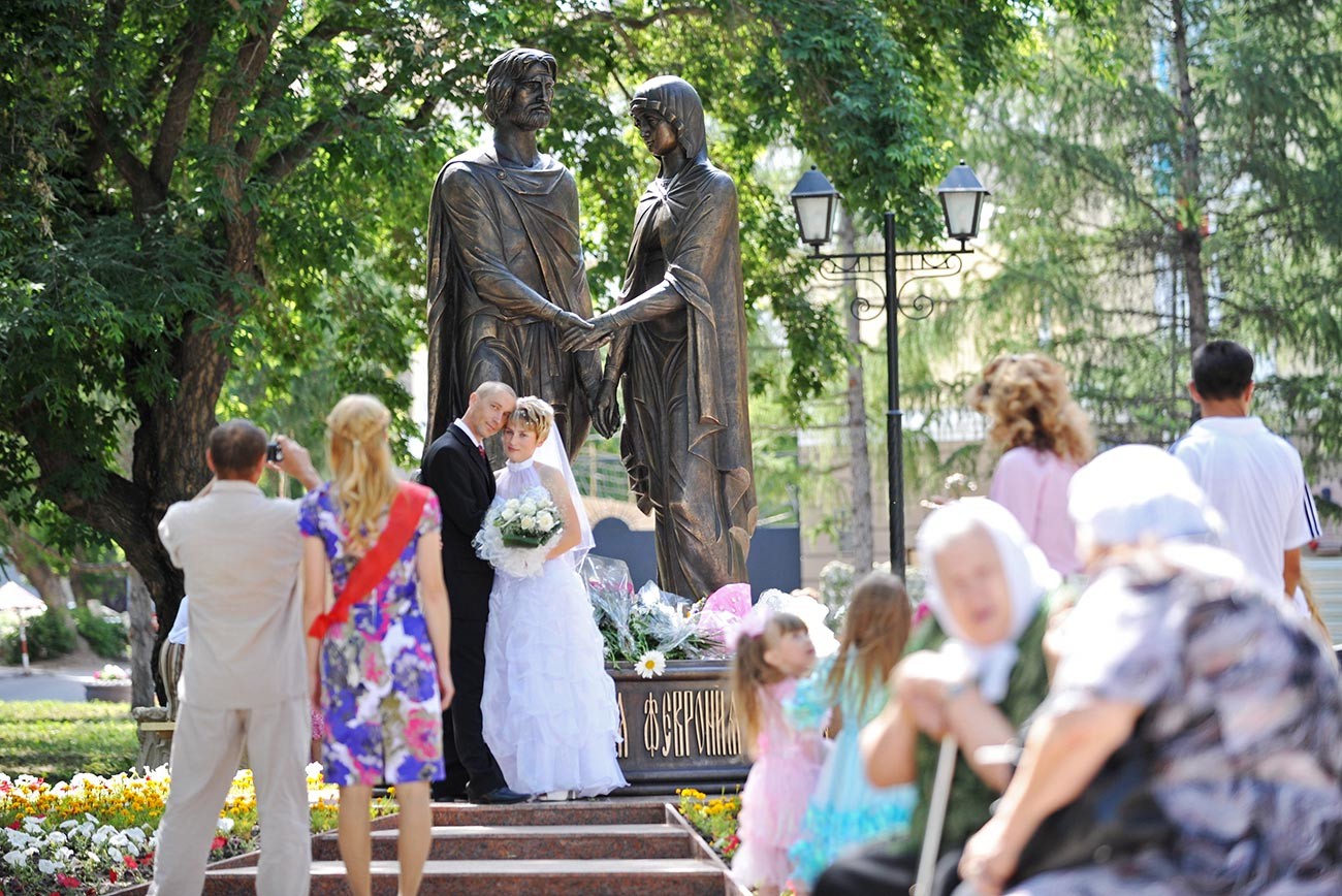 Newlyweds take photos at the Peter and Fevronia statues in Omsk.