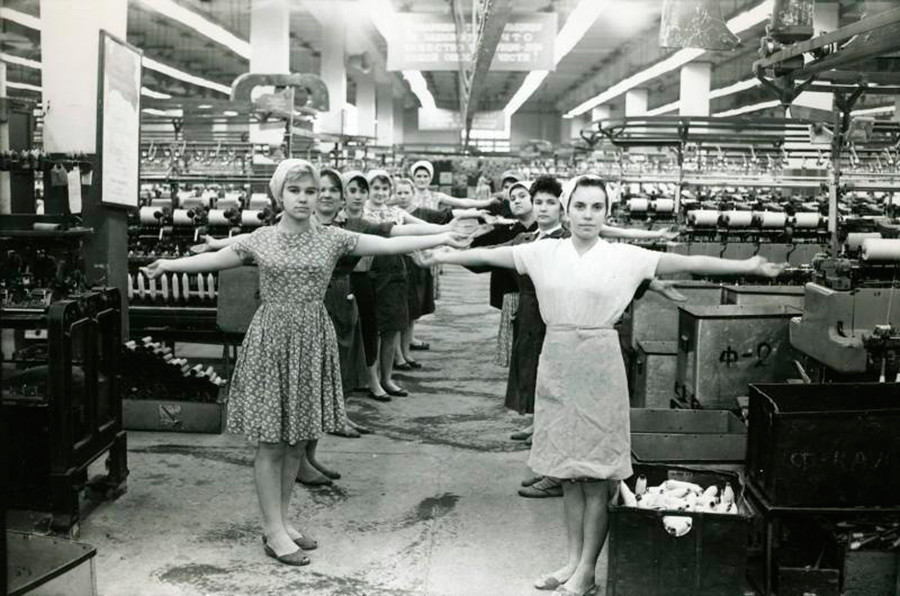 Des ouvriers d'une usine de textile s’étirent avant de prendre leur poste, 1960