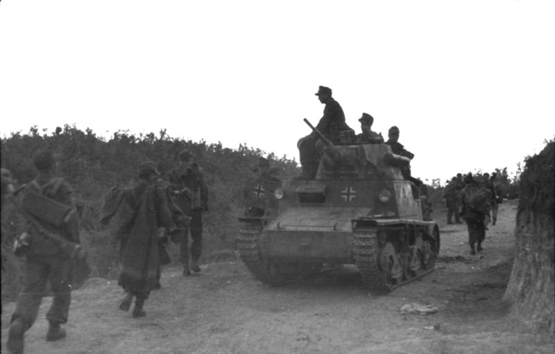 Soldados alemanes en marcha, tanque italiano Carro armato L.6/40 con insignia alemana.